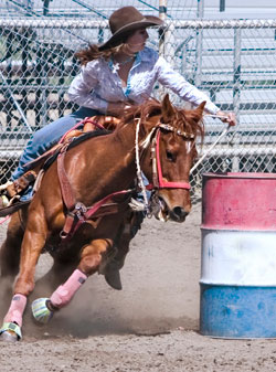 cowboy racing around a barrel on a horse